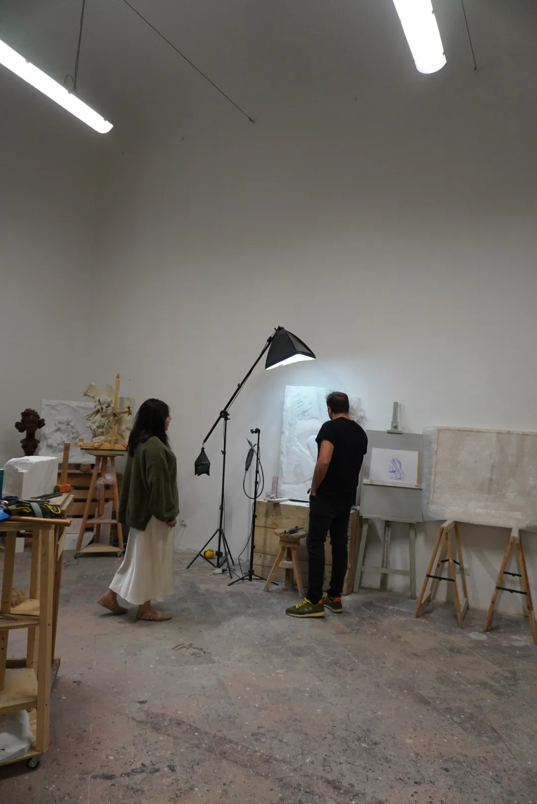 Frida y Enrico Ferrarini frente a un relieve de mármol, entre moldes y esculturas de escayola